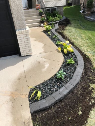 Stack Stone flower gardens with plants completed by Genesis Interlocking & Custom Landscaping in Winnipeg