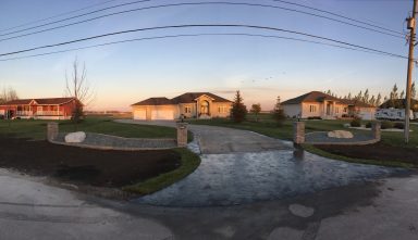 Stamped concrete driveway approach with pillars and rock garden box completed by Genesis Interlocking & Custom Landscaping in Winnipeg