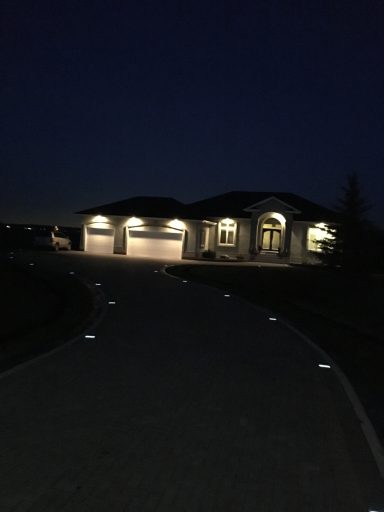 Night shot of low voltage LED lighting on an interlocking paver driveway completed by Genesis Interlocking & Custom Landscaping in Winnipeg