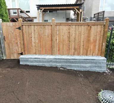 Allan Bloc retaining wall to support grade & pressure treated fence completed by Genesis Interlocking & Custom Landscaping in Winnipeg