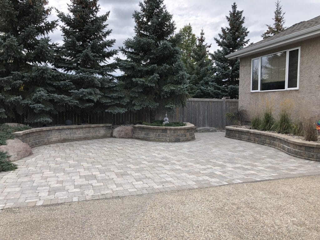 Barkman roman paver patio with retaining wall flower garden installed in Winnipeg Manitoba by Genesis Interlocking & Custom Landscaping
