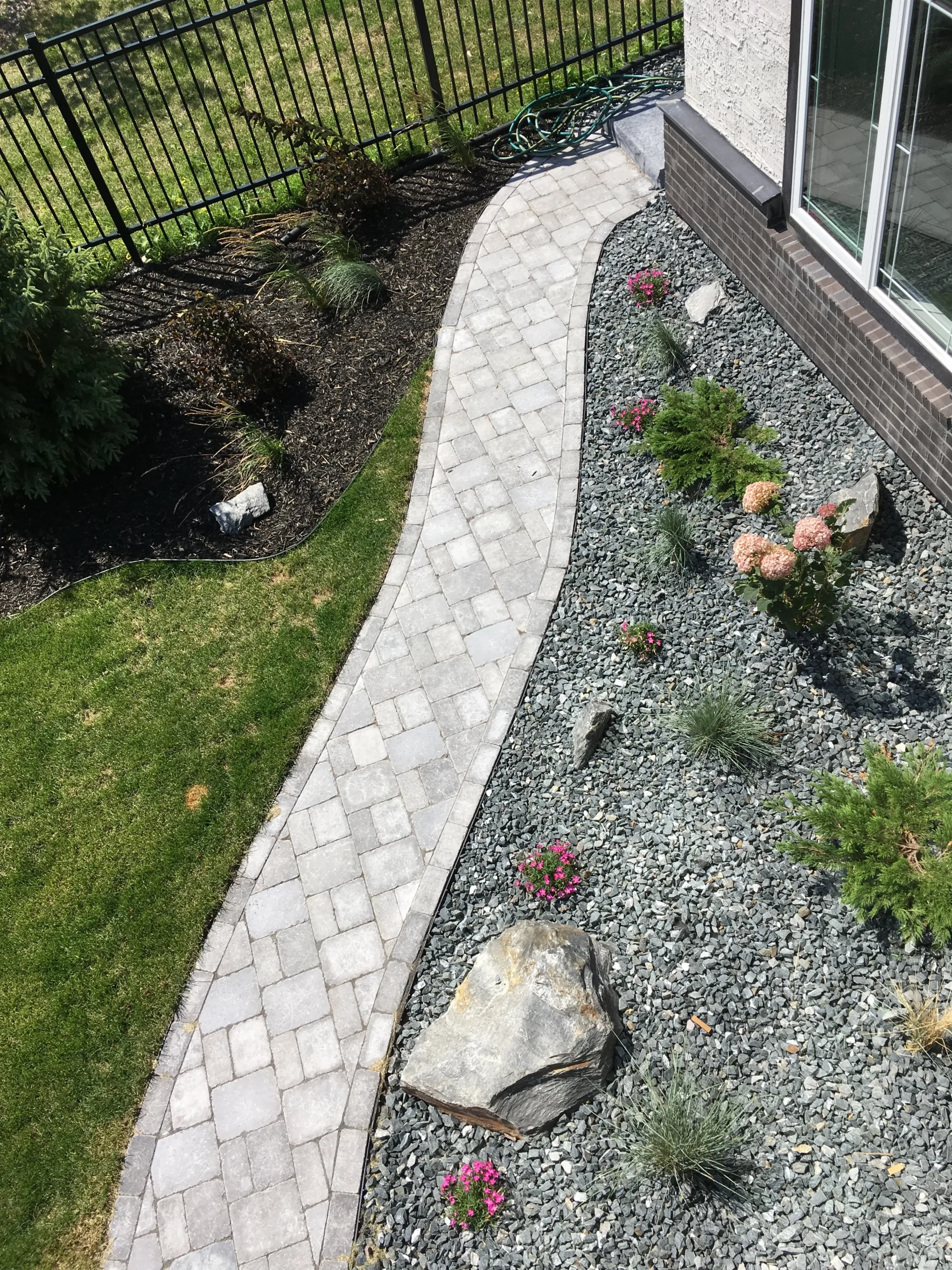 Roman paver sidewalk installation with landscaping, decorative rock, plants & boulders