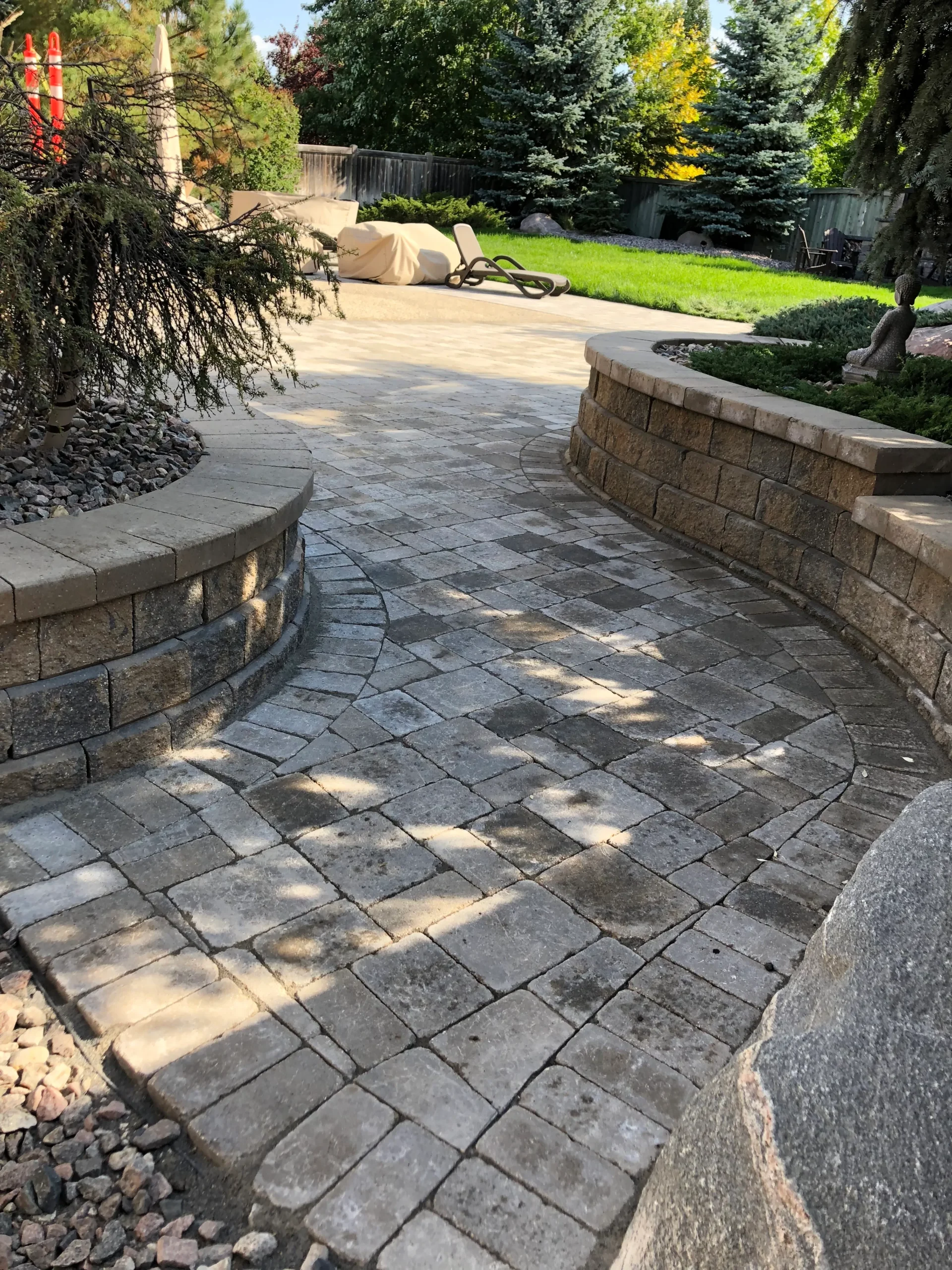 Roman paver patio with retaining wall flower gardens. Fully grown plants & trees
