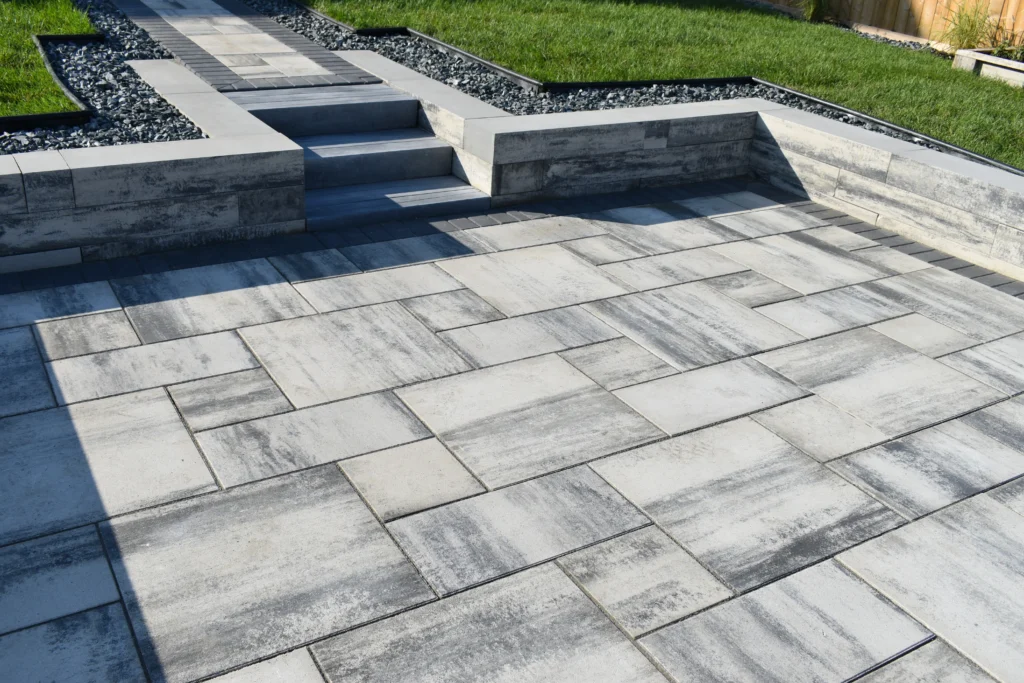 Sunken Barkman Broadway paver patio with architexture retaining wall, black granite & sod