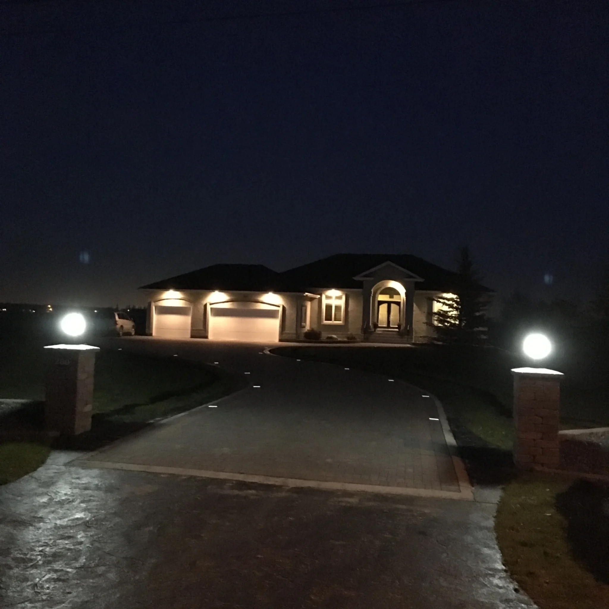 Night shot of Barkman Holland paver driveway with low voltage lighting, pillars & concrete curbing / approach