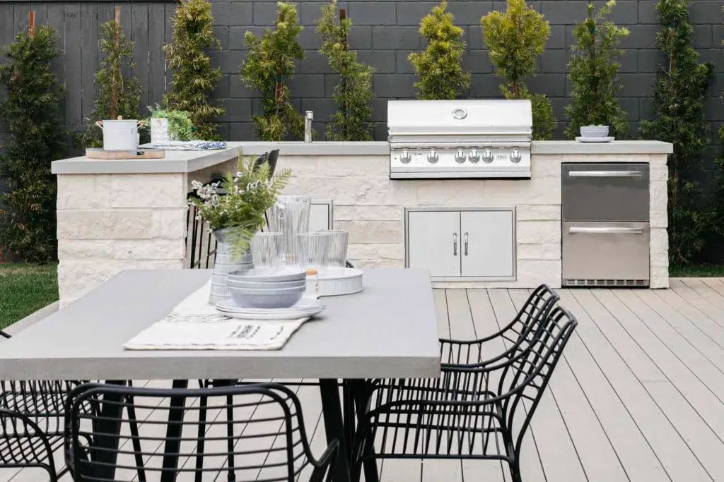 Custom outdoor kitchen with a built-in grill and counter space in a backyard with patio table and chairs 
