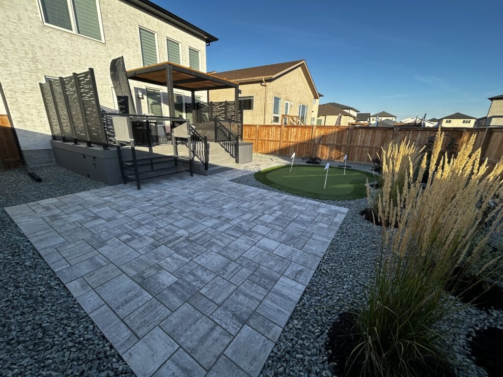 backyard landscaping with interlocking patio, putting green, composite deck and plants