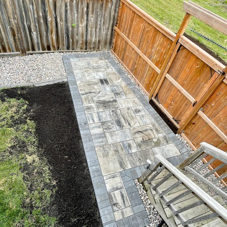 Barkman Broadway 65mm paver patio in sterling with charcoal border and pressure treated fence completed by Genesis Interlocking & Custom Landscaping - Winnipeg Paving Stone Contractor