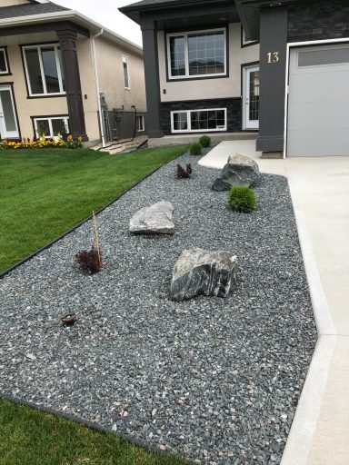 Front yard decorative rock, boulders and shrubs completed by Genesis Interlocking & Custom Landscaping