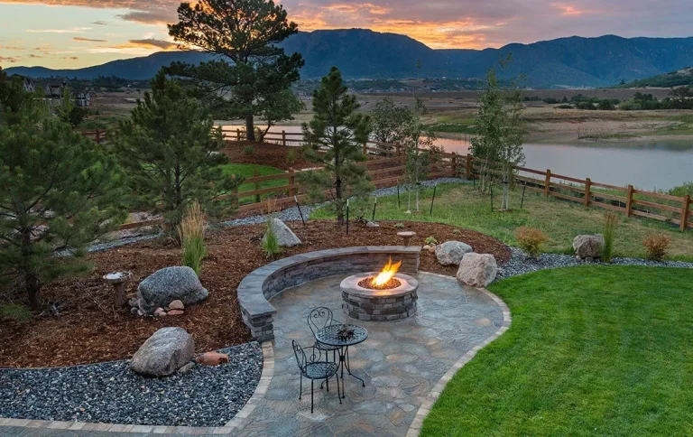 Cottage landscaping patio fireplace and seating wall with custom landscaping & a beautiful sunset over the mountains