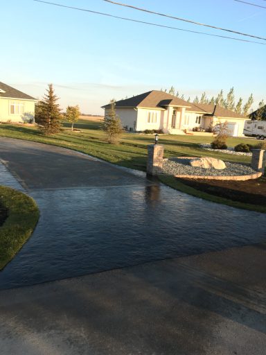 Stamped concrete driveway approach with pillars and rock garden box completed by Genesis Interlocking & Custom Landscaping