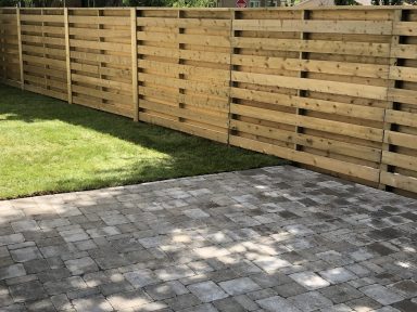 Barkman Roman paver patio and custom cedar fence in natural grey completed by Genesis Interlocking & Custom Landscaping
