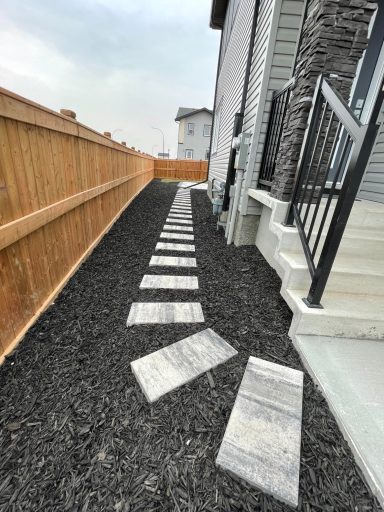 Black mulch with stepping stone walkway completed by Genesis Interlocking & Custom Landscaping