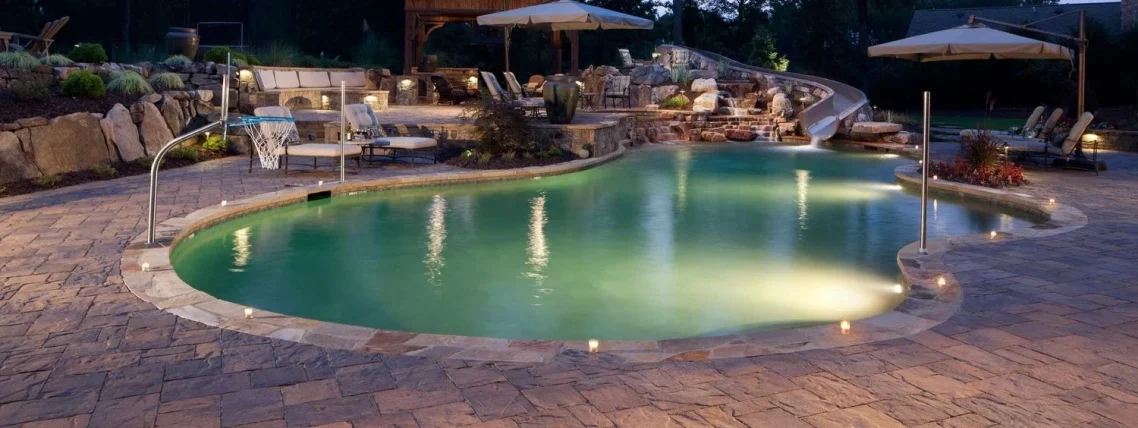 Custom landscaped backyard with inground swimming pool, waterslide and basketball net