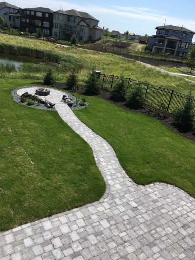 Barkman Roman paver patio and sidewalk leading down to sunken patio in natural grey completed by Genesis Interlocking & Custom Landscaping