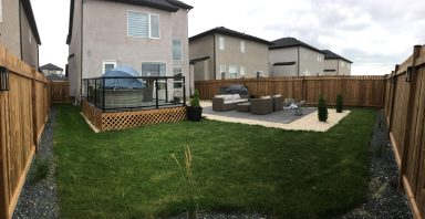 Full yard shot with pressure treated 4x4 fence, composite deck with glass railings and interlocking patio area completed by Genesis 