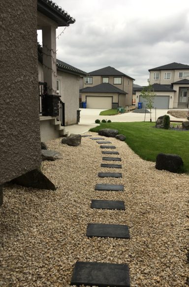 Front yard decorative rock, boulders and stepping stones completed by Genesis Interlocking & Custom Landscaping